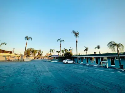 a parking lot with a car parked in front of a motel at King's Inn Motel in Kingsburg