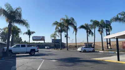 a white truck parked in a parking lot with palm trees at King's Inn Motel in Kingsburg