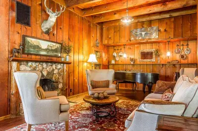 a living room with a fireplace and a piano at Sierra Sky Ranch in Oakhurst