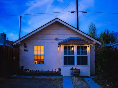a small white house with lights in the window at Cozy Muir Cottage - In Town - Pet Friendly in Lone Pine