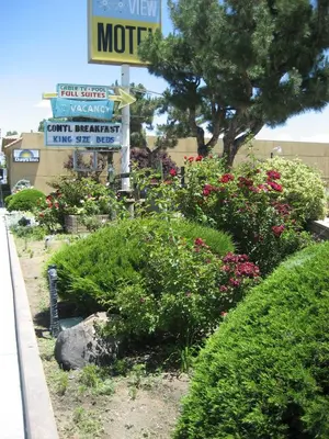 a sign for a motel with some bushes and flowers at Mountain View Motel in Bishop
