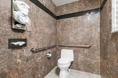 a bathroom with a toilet and a stone wall at Country Inn Sonora in Sonora