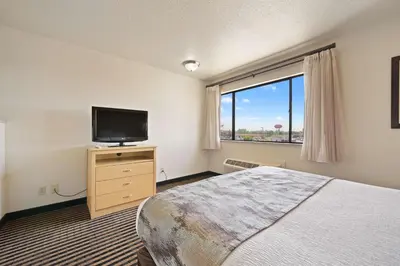 a bedroom with a bed and a tv and a window at Best Western Plus Executive Inn & Suites in Manteca