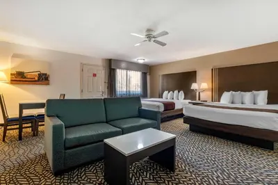 a hotel room with two beds and a couch at Best Western Orchard Inn in Turlock