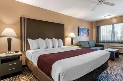 a hotel room with a large bed and a chair at Best Western Orchard Inn in Turlock