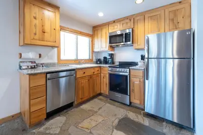 a kitchen with wooden cabinets and a stainless steel refrigerator at Red Wolf Lakeside Lodge in Tahoe Vista