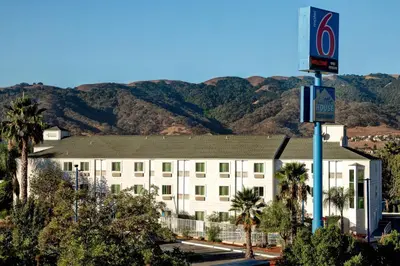 a hotel with a building with mountains in the background at Motel 6-Gilroy, CA in Gilroy