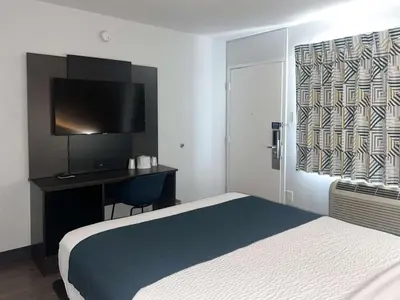 a bedroom with a bed and a desk with a television at Motel 6-Tulare, CA in Tulare
