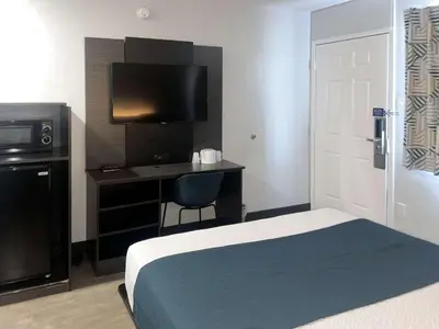 a bedroom with a bed and a desk with a television at Motel 6-Tulare, CA in Tulare