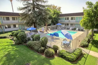 an overhead view of a swimming pool with umbrellas and bushes at Motel 6-Porterville, CA in Porterville