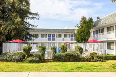 a building with chairs and umbrellas in front of it at Motel 6-Porterville, CA in Porterville