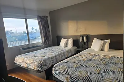 a hotel room with two beds and a window at Super 8 by Wyndham Tracy in Tracy