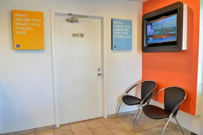 two chairs and a television in a room with orange walls at Motel 6 - Santa Nella, on i-5 in Santa Nella Village