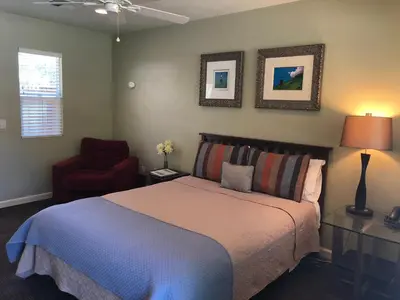 a bedroom with a bed and a red chair at Queen's Inn By The River in Oakhurst