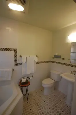 a bathroom with a toilet and a tub and a sink at Queen's Inn By The River in Oakhurst