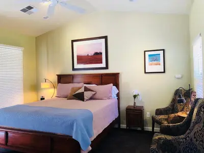 a bedroom with a bed and two chairs at Queen's Inn By The River in Oakhurst