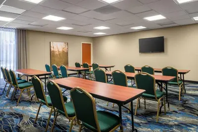 a conference room with tables and chairs and a screen at Fairfield Inn & Suites by Marriott Visalia Tulare in Tulare