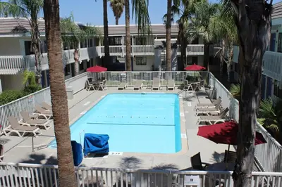 a swimming pool in a resort with palm trees and chairs at Motel 6-Coalinga, CA - East in Coalinga