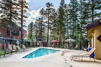 a swimming pool with chairs and an umbrella at Courchevel 14 Condo in Mammoth Lakes
