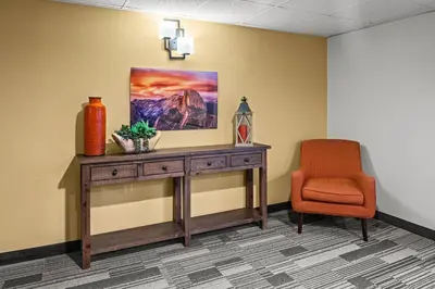 a room with a desk and a chair and a painting at Yosemite Southgate Hotel & Suites in Oakhurst