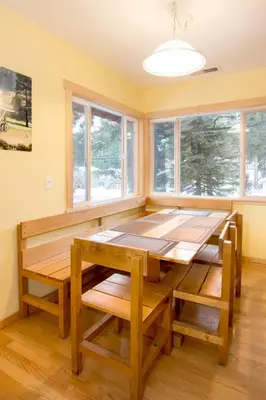 a dining room with a wooden table and windows at Edelweiss Lodge in Mammoth Lakes