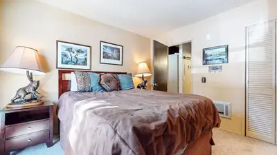 a bedroom with a large bed and a table with a lamp at Bigwood #62 Condo in Mammoth Lakes