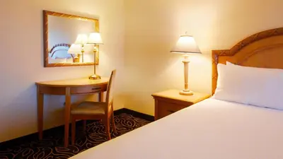 a hotel room with a bed and a desk and a mirror at Eldorado Reno, A Caesars Destination in Reno