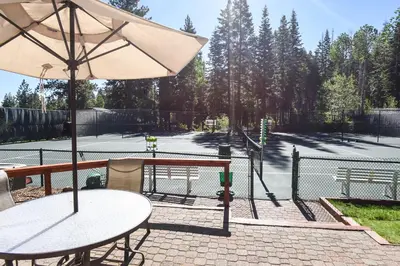 a table with an umbrella next to a tennis court at Gold Bend 5022 in Truckee