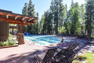 a swimming pool with chairs and a person in the water at Northstar Village 216 in Truckee