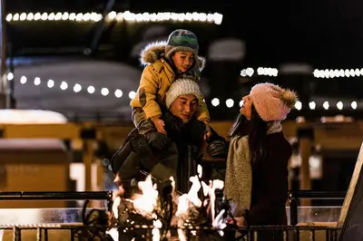a man with a child on his shoulders next to a fire at Northstar Village 216 in Truckee