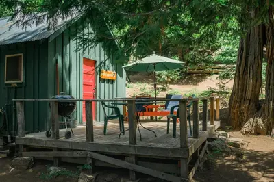 a green cabin with a table and an umbrella at Silver City Mountain Resort in Sequoia National Park
