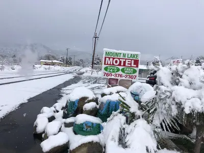 a motel sign in the snow next to a road at Mount-N-Lake Motel in Wofford Heights