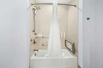 a bathroom with a shower with a white tub at Hampton Inn Morgan Hill in Morgan Hill