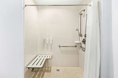 a white shower with a bench in a bathroom at Hampton Inn Morgan Hill in Morgan Hill
