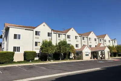 a large white apartment building on a street at Microtel Inn & Suites, Morgan Hill in Morgan Hill