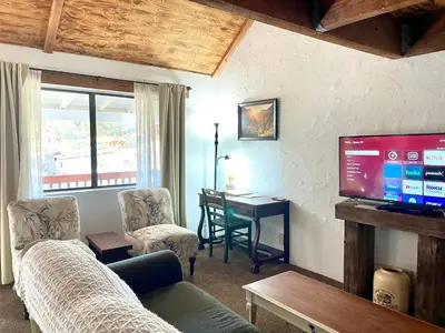 a living room with a couch and a table with a television at Sierra Mountain Lodge - Vacation Rentals - Yosemite in Ahwahnee