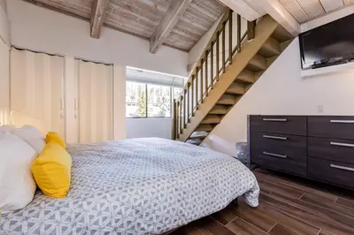 a bedroom with a bed with a television and stairs at Courchevel C # 9 in Mammoth Lakes