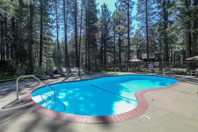 a swimming pool with chairs and trees in the background at Sunshine Village #158 in Mammoth Lakes