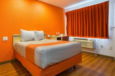 a bedroom with a bed with an orange wall at Motel 6 Lost Hills / Buttonwillow Racetrack in Lost Hills