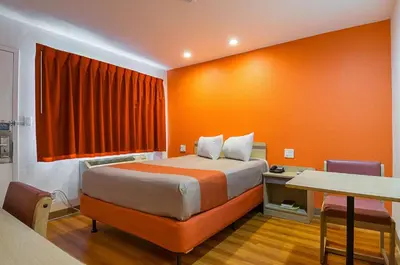 a bedroom with a bed with an orange wall at Motel 6 Lost Hills / Buttonwillow Racetrack in Lost Hills