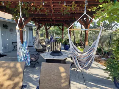 a patio with chairs and hammocks under a pergola at Yosemite Foothill Retreat in Coarsegold