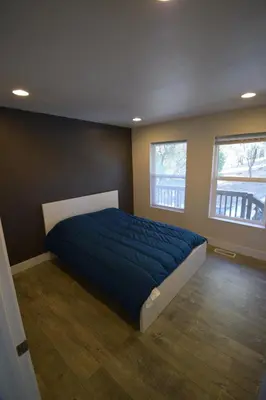 a bedroom with a bed with a blue comforter and two windows at Mountain Place in Groveland