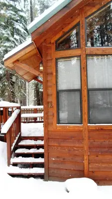 a cabin in the snow with a porch at Cedar Pines Resort in South Lake Tahoe