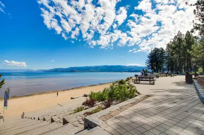 a beach with people sitting on a bench next to the water at Elegant Pine in South Lake Tahoe