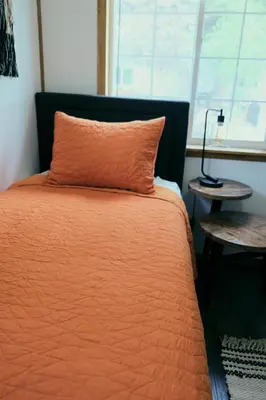 an orange bed with an orange pillow and a window at Lake Front Cabins in June Lake