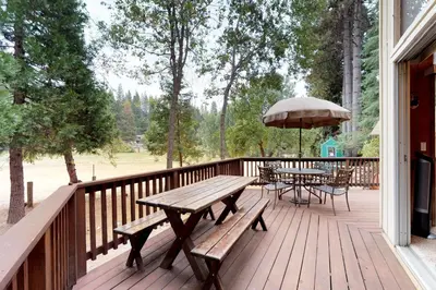 a wooden deck with benches and tables with an umbrella at Bears Meadow in Arnold