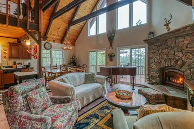 a living room with a stone fireplace and a piano at Forest Bears Hideout in Arnold