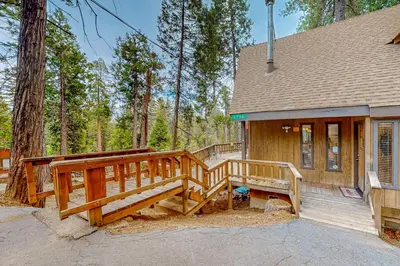 a house with a large wooden deck in the woods at Mitthas Tapovan in Arnold