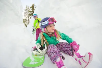 a little girl sitting in the snow with a snowboard at L306 Kirkwood Lodge in Kirkwood
