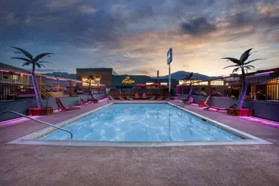 a pool at a hotel with chairs and palm trees at Travelodge by Wyndham Hawthorne in Hawthorne